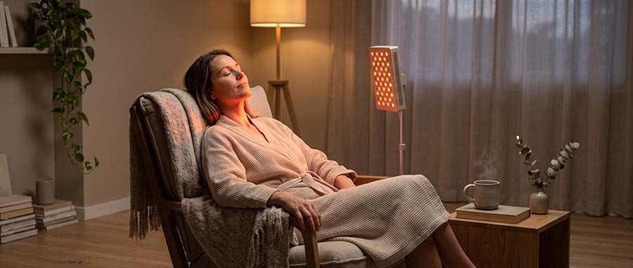 femme se détendant pendant une séance de luminothérapie rouge à domicile avec un panneau RedLightLux dans le cadre d'une routine quotidienne pour la production de collagène et le rajeunissement de la peau